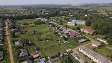 Nema, Kirov Bölgesi 'nde güneş ışığı altında küçük kır evleri arasında yeşil ağaçların ve çayırların hava manzarası