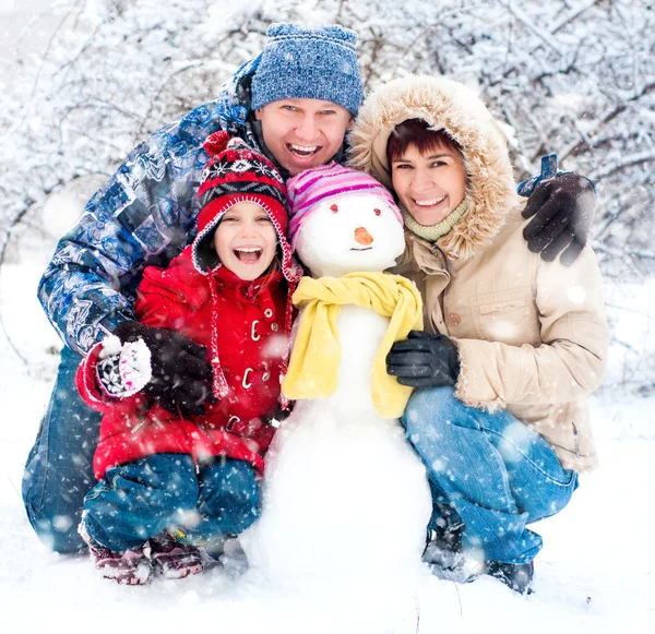 Familia feliz con muñeco de nieve — Foto de Stock