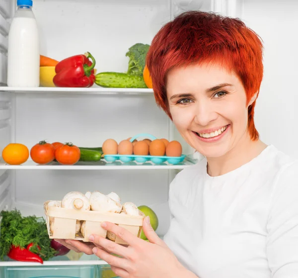 Vrouw tegen de koelkast — Stockfoto