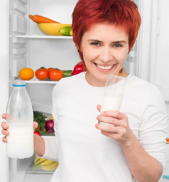 Vrouw tegen de koelkast — Stockfoto