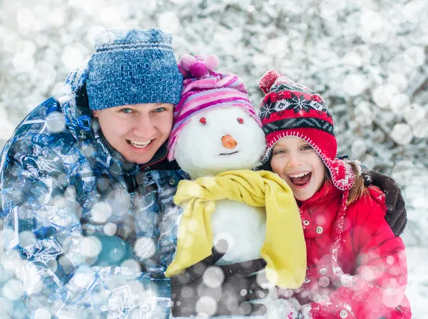 Familia con un muñeco de nieve —  Fotos de Stock