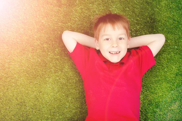 男孩躺在绿色的草坪上 — 图库照片