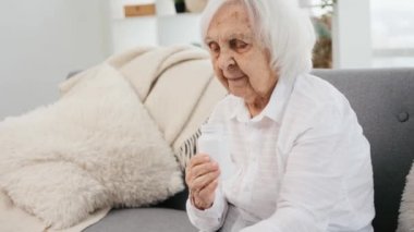 Yaşlı kadın hap alıyor.