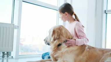 Golden Retriever köpeğiyle oturan küçük kız