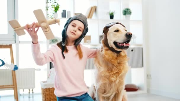 小さな女の子と黄金の取得犬でパイロット帽子 — ストック動画