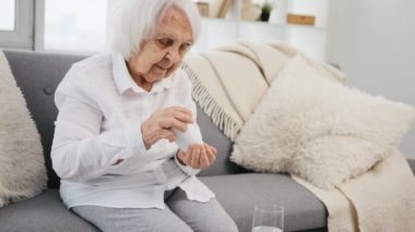 Yaşlı kadın hap alıyor.