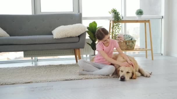 Flicka petting golden retriever hund — Stockvideo