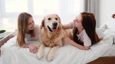 Yatağında Golden Retriever köpeği olan kızlar