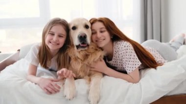 Yatağında Golden Retriever köpeği olan kızlar