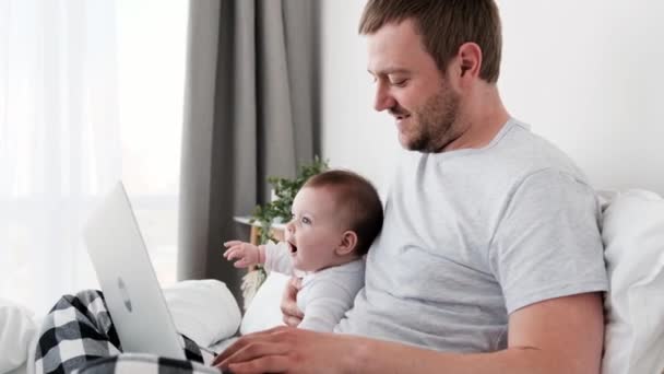 Père avec enfant et ordinateur portable dans le lit — Video