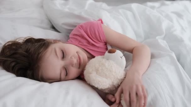 Niño con oso de peluche en la cama — Vídeos de Stock