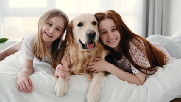 Дівчата з золотою собакою-ретривером у ліжку — стокове відео