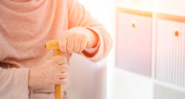 Manos de anciana sosteniendo bastón — Foto de Stock