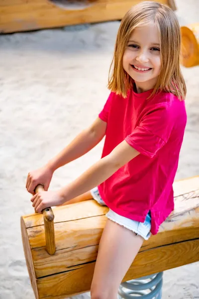 Kleines Mädchen reitet Schaukel auf Spielplatz — Stockfoto