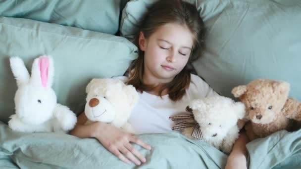 Дівчина з плюшевими ведмежими іграшками в ліжку — стокове відео