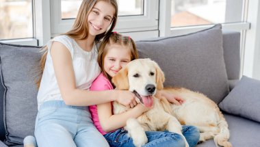 Gülümseyen kızlar sevimli köpekleri kucaklıyor.