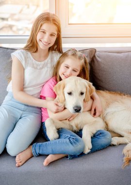 Mutlu kız kardeşler sevimli köpekleri kucaklıyor.