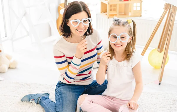 Menina e mãe segurando óculos de pau — Fotografia de Stock