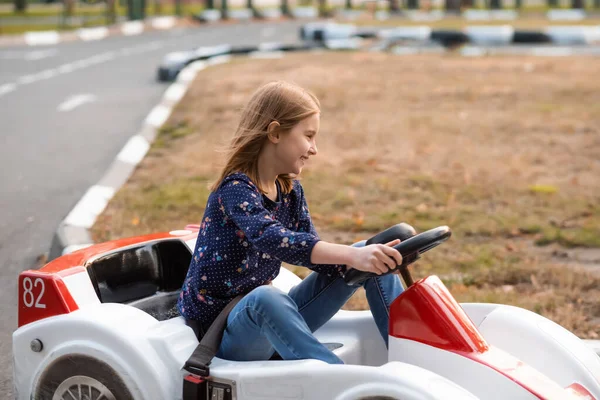 Счастливая девочка за рулем картинга в парке — стоковое фото