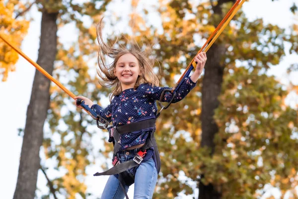 Trambolin iplerinde hoplayıp zıplayan mutlu küçük kız — Stok fotoğraf