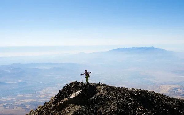 Turista in cima alla montagna con le mani alzate — Foto Stock