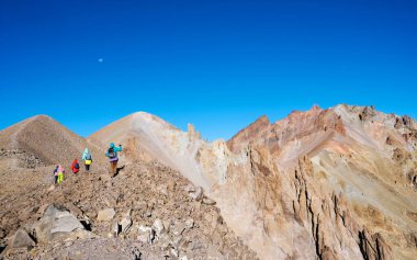 Bir grup dağcı taşlı dağlara tırmanıyor.