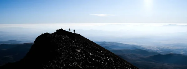 Silueta de excursionistas en la cima de la montaña — Foto de Stock