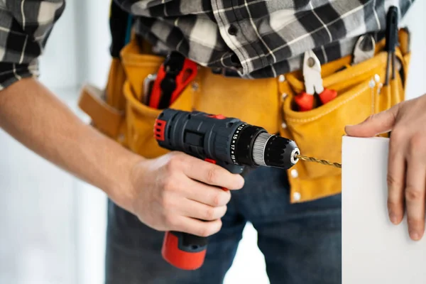 Worker in tool belt drilling furniture board — Stock Photo, Image