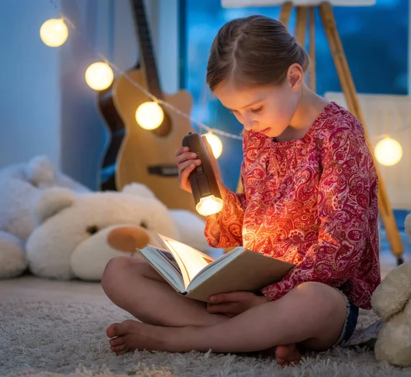 Cute little girl czytania książki w nocy — Zdjęcie stockowe