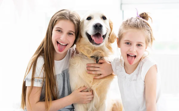 Uśmiechnięte siostry z uroczym psem — Zdjęcie stockowe