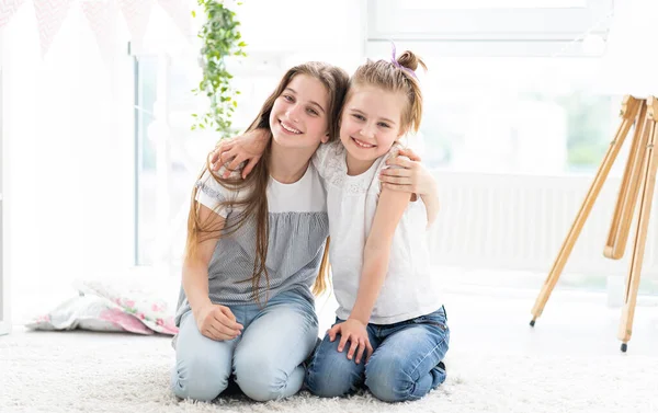 Irmãs felizes abraçando no quarto brilhante — Fotografia de Stock