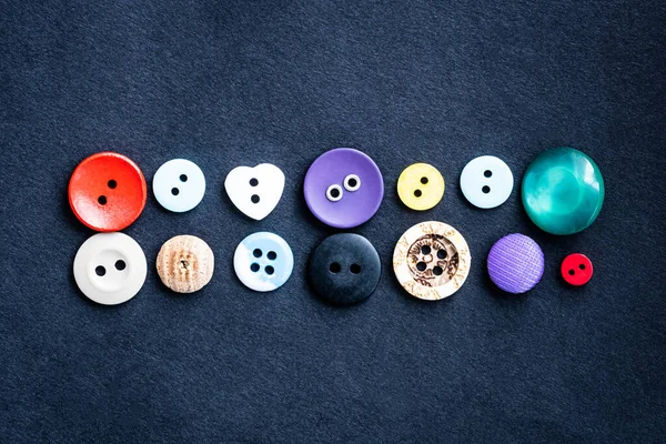 Botões de costura deitado em pano escuro — Fotografia de Stock