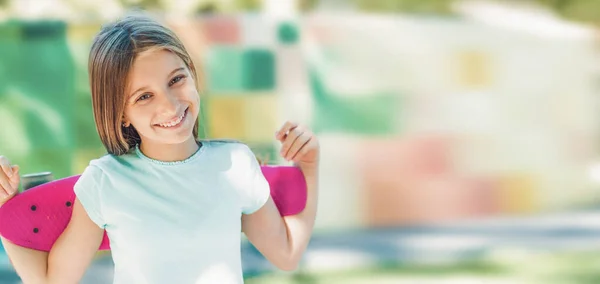 Usmívající se dívka drží růžový skateboard — Stock fotografie
