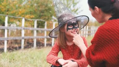 Mother painting art on girl for halloween