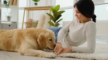 Golden retriever köpeğiyle oynayan genç bir kadın.