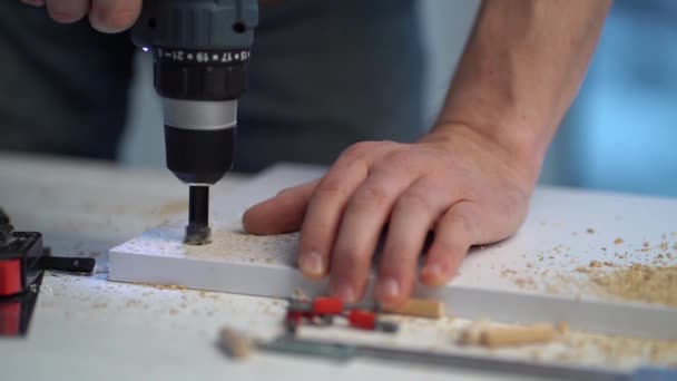 Man making hole in board using drill — Stockvideo