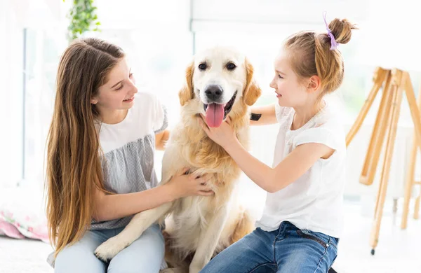 Leuke zusjes die dollen met hond — Stockfoto