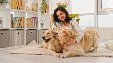 İki golden retriever köpeğiyle halıda oturan ve gülümseyen mutlu güzel kız.