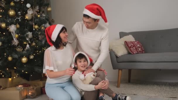 Gelukkig Familie Rood Santa Hoeden Zitten Buurt Van Kerstboom Thuis — Stockvideo