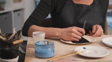 Atölyede el yapımı desen için fırça kullanan kadın tabağı