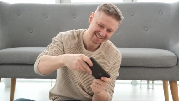 Knappe Man Vloer Spelend Smartphone Lachend Volwassen Man Zoek Naar — Stockvideo