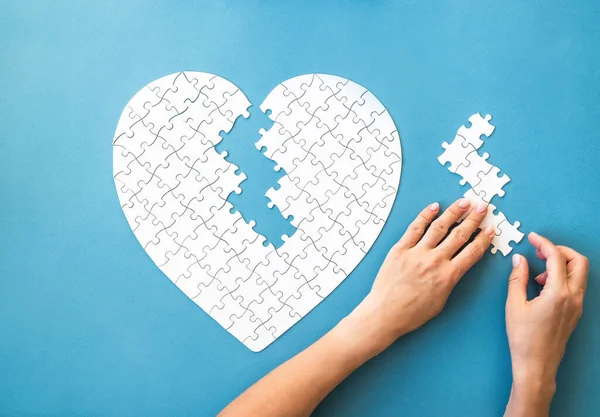 White Puzzle Heart Shape White Details Puzzle Hands Blue Background — Stock fotografie