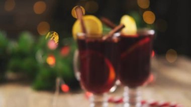 Tarçınlı çubuklar ve limonlu dilimler köpüklü çelenk arka planında sıcak şarap.