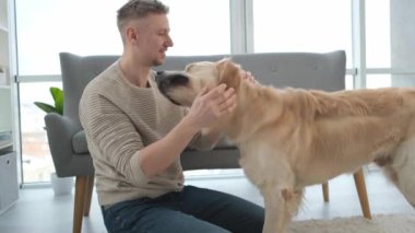 Golden Retriever köpeğiyle yerde oturan ve onu okşayan bir adam. Evcil köpek labrador 'u olan yetişkin bir adamın portresi.