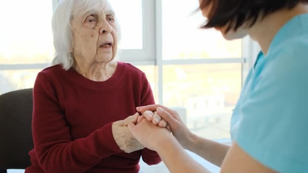 Віці Жінка Розмовляє Медсестрою Тримаючи Руки Сидячи Стільці Будинку Престарілих — стокове відео