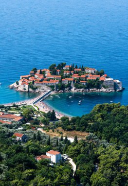Karadağ 'daki güzel Sveti Stefan adası ve yukarıdaki orman. Akdeniz kıyısındaki Adriyatik denizi ve lüks tatil beldesinin manzarası