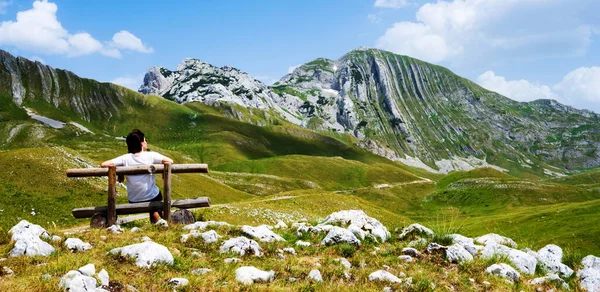 女の子モンテネグロの山の中で木製のベンチに座って振り返ってみる 国立公園で休んでいる若い女の子 自然の景色を望むデュルモーター — ストック写真