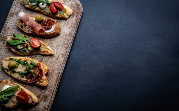 配上果酱 烤樱桃西红柿的红辣椒放在木板上 背景上配上阿鲁古拉 并留有复制空间 地中海烤面包 奶酪和蔬菜 — 图库照片