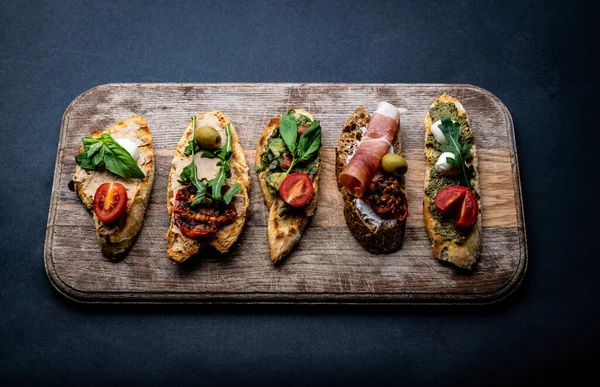 Bruschettas Mit Marmelade Oliven Pesto Gegrillten Kirschtomaten Serviert Auf Holzbrett — Stockfoto