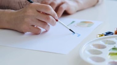 Sanat dersinde suluboya boyayla basit işler yapan yetenekli bir kız.